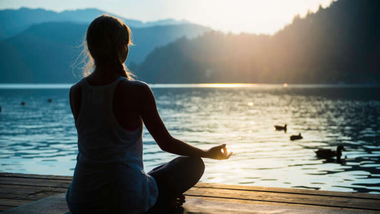 Vrouw mediteren op de oever van het meer